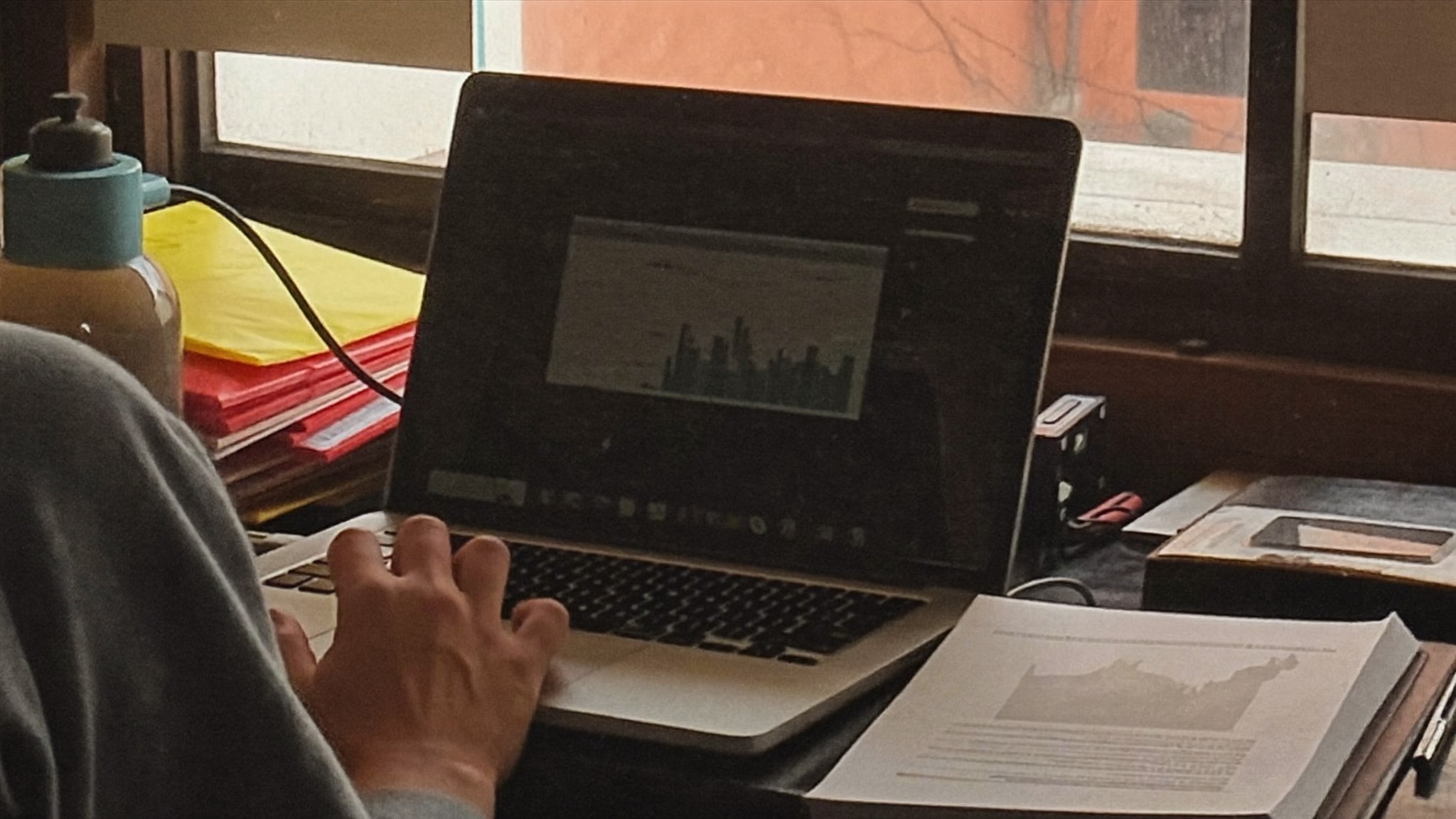A small business owner reviewing marketing performance numbers on a laptop at a workshop desk in natural light