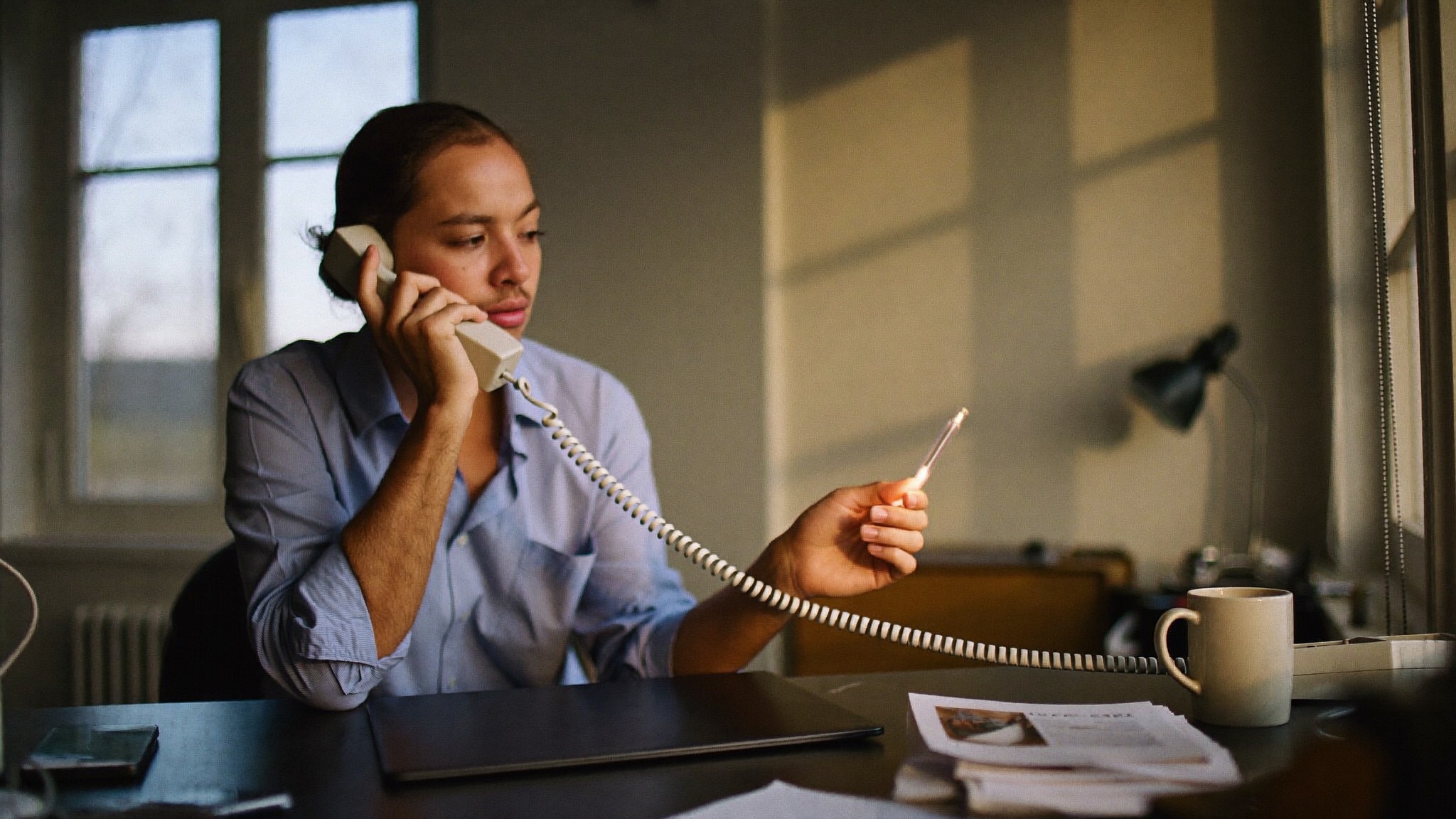 A small business owner at a desk looking at a laptop with a phone ringing, weighing whether to run ads or invest in getting found organically